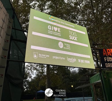 SummerStage screen in Central Park listing Global Lyme Alliance as Community Partner for Music for Action alongside the Steven and Alexandra Cohen Foundation and Ticks Suck